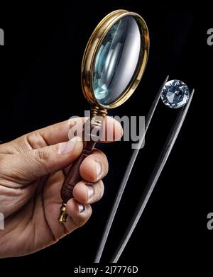 Large gemstone and loupe in jeweler's hands close up. Gem identifying and evaluating process. Stock Photo