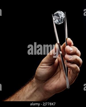 Large gemstone in jeweler's hand close up. Gem identifying and evaluating process. Stock Photo