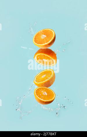 oranges fly on a blue background in water drops Stock Photo