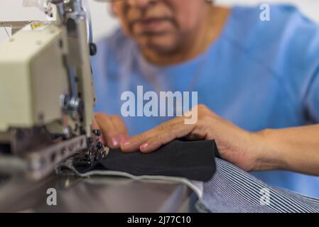 Close up of a mature latin woman using a sewing machine Stock Photo