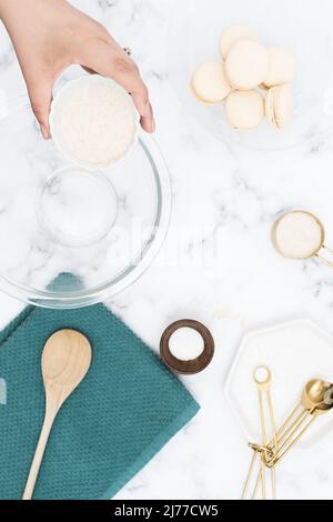 female hand adds flour to mixing bowl surrounded by baking utensils Stock Photo