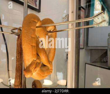 A plain, unsalted pretzel in a glass case with a heating element; warm plain pretzel on display for sale to customers. Stock Photo
