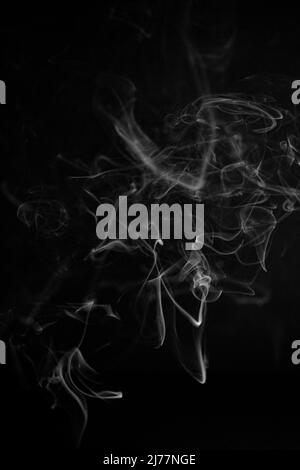 A white, swirling, ascending smoke pattern on a black background, photo could be used as a background, smoke texture or abstract, or general stock pho Stock Photo