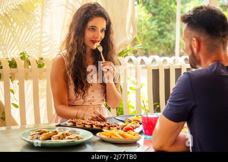 indian couple eating in summer tropical cafe , focus on girl Stock Photo