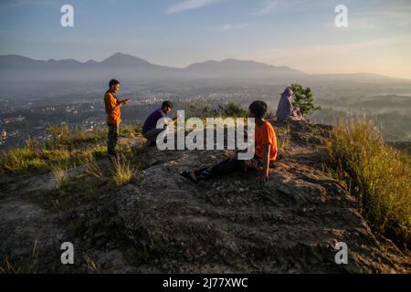Sumedang, West Java, Indonesia. 7th May, 2022. People took a picture with the backdrop of natural scenery on May 7, 2022 at Mount Batu Tanjungsari, Sumedang Regency, Indonesia. Mount Batu Tanjungsari is one of the tourist destinations for people to spend the Eid al-Fitr holiday 1443 H with their families. (Credit Image: © Algi Febri Sugita/ZUMA Press Wire) Stock Photo