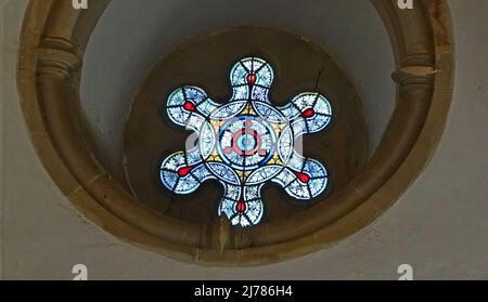 A beautiful stained glass window in an old manor. It's a round window in the form of a flower. It's placed in a thick sandstone wall Stock Photo