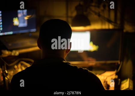Hacker at computer. Man in dark. Silhouette of person working on Internet. Stock Photo