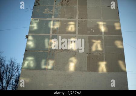 Light on wall of house. Reflection from windows on wall. Light shows symbols on wall. Stock Photo