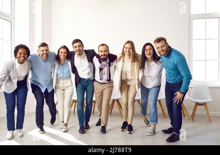 Team of young and successful multiracial people hug and smile at camera together. Stock Photo