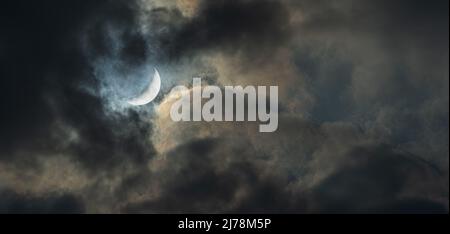 Photograph of New Moon in the cloudy gloomy night sky. Stock Photo