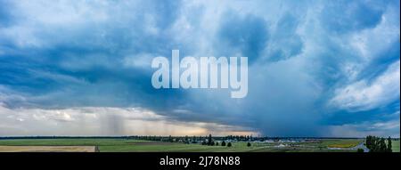 Dramatic stormy dark cloudy sky over village. Beautiful nature background. Stock Photo