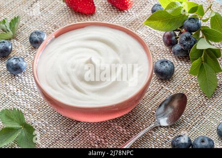 Ceramic bowl with plain yoghurt and berries on the table. Light summer mood. Stock Photo