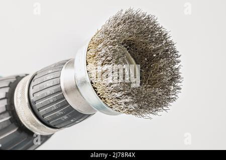 Close-up view of hand drill with round steel brush on white background Stock Photo