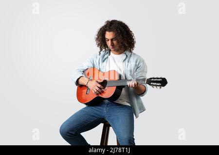 Young man playing acoustic solo guitar, isolated on white background. High quality photo Stock Photo