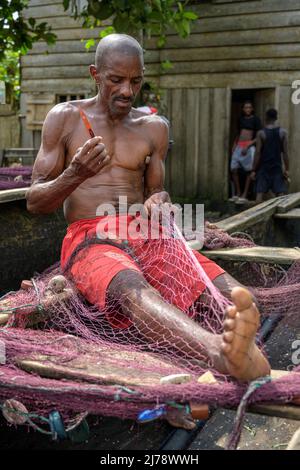 Fisherman repairing the fishing nets on the canoe before going out to fish. Stock Photo