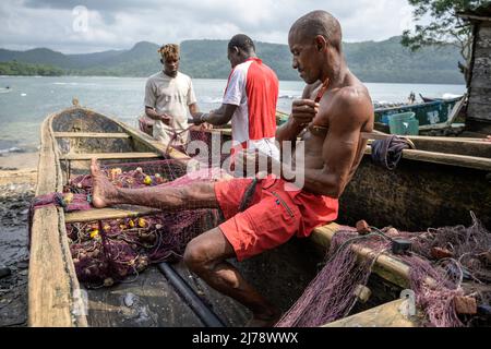 Fishermen repairing the fishing nets on the canoe before going out to fish. Stock Photo