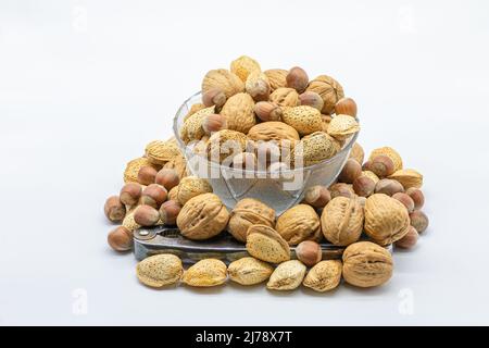 Walnuts, hazelnuts and almonds in a glass bowl with a nutcracker, isolated on a white background Stock Photo