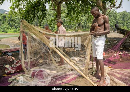 Fishermen repairing the fishing nets before going out to fish. Stock Photo