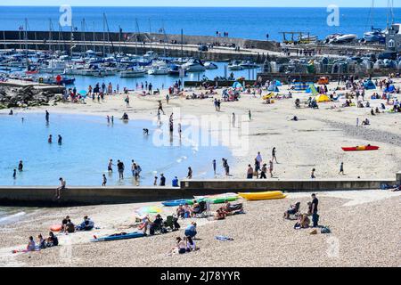 Lyme Regis, Dorset, UK. 7th May 2022. UK Weather: Crowds flock to the beach at the seaside resort of Lyme Regis to soak up the hot sunshine and clear blue skies as the May heatwave kicks in on what is set to be the hottest day of the year so far. Credit: Celia McMahon/Alamy Live News. Stock Photo