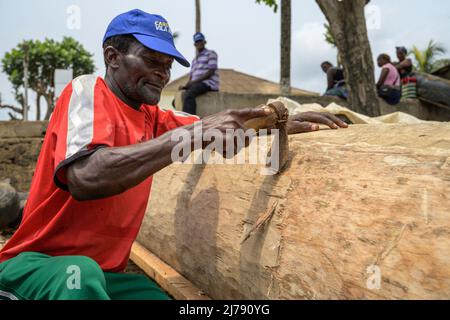 Man hand carving a large log to make a canoe Stock Photo - Alamy