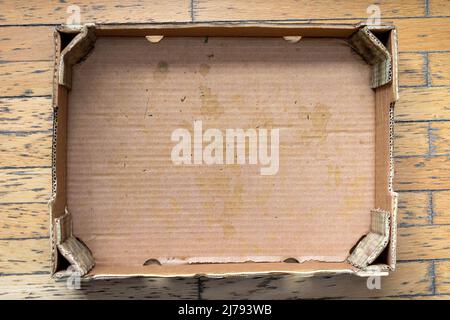 Empty dirty used cardboard box on wooden floor Stock Photo