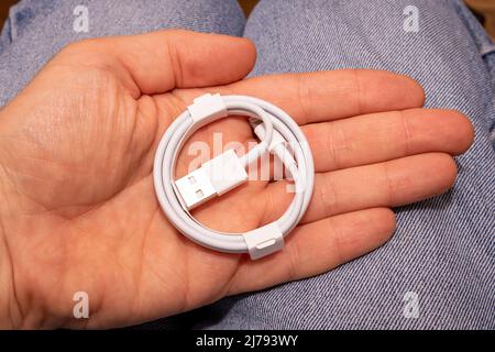 Folded connection data USB to lightning cable in mens hand Stock Photo