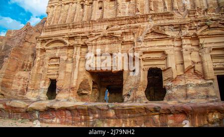 Mature woman poses in Petra Jordan in front of the temple wearing a blue scarf and enjoying the beautiful landscape carved into the rock in Petra Jord Stock Photo