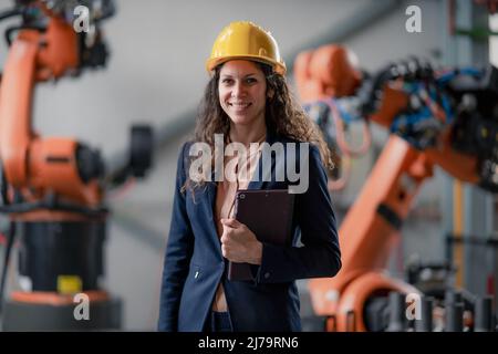 Automation female engineer with tablet for programming robotic arm in factory. Stock Photo