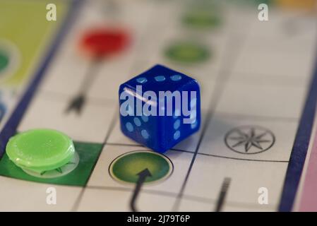 Blue dice on a Ludo boardgame board. Stock Photo