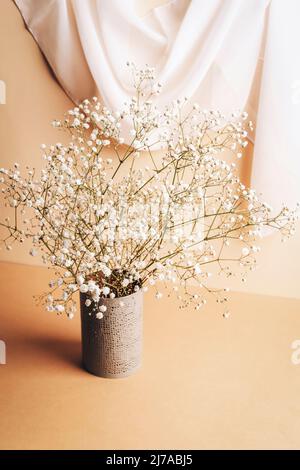 Gypsophila flowers in vase on beige table. Still life. Stock Photo