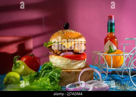 Chicken Cheese Burger with tomato, ketchup and green chilli isolated on wooden board side view of american fast food Stock Photo