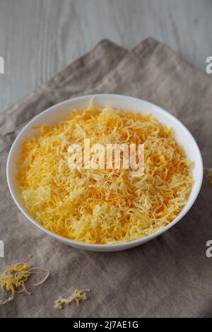 Shredded Mexican Cheese Mix in a White Bowl, side view. Stock Photo
