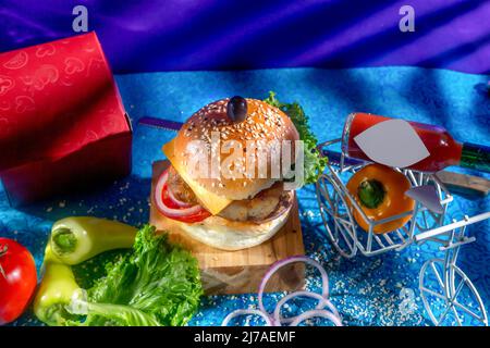 Chicken Cheese Burger with tomato, ketchup and green chilli isolated on wooden board side view of american fast food Stock Photo