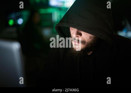 Criminal team Hacker using computer for organizing massive data breach attack on government and big company servers. Dark room surrounded computers Stock Photo