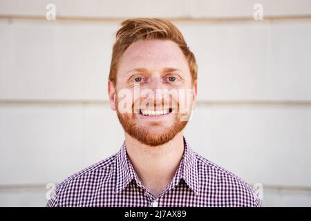 Outdoor portrait of a smiling Red hair guy looking at the camera laughing with positive face and friendly look. Close up of a Happy human face - Stock Photo