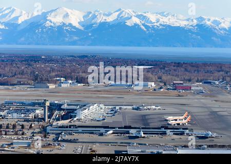 Anchorage Airport terminal aerial view in Alaska with mountain behind. Ted Stevens Anchorage International Airport seen from above. Stock Photo