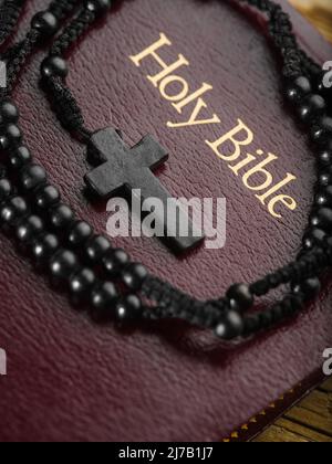 Rosary with a crucifix and the Holy Bible. Macro shot. Symbols of Christianity, Catholicism. Holy scripture, prayer, meditation, spirituality, faith, Stock Photo