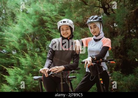 two women in veil happy while cycling together Stock Photo