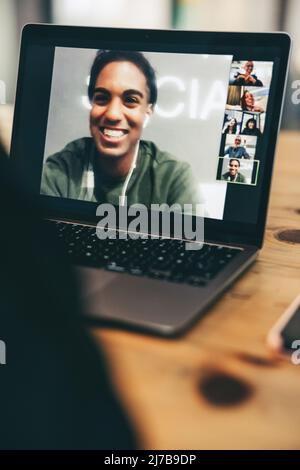 Anonymous entrepreneur attending a virtual meeting in an office. Unrecognisable businessperson using a laptop for a video conference with their partne Stock Photo