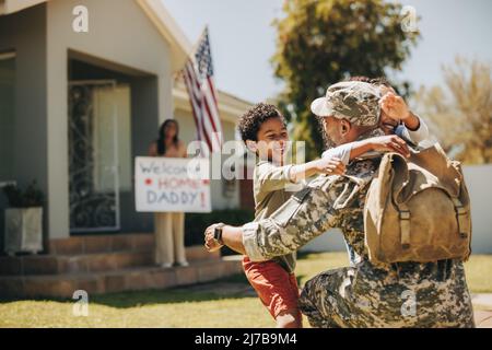 Military dad reuniting with his family at home. American soldier embracing his children after coming back home from the army. Serviceman receiving a w Stock Photo