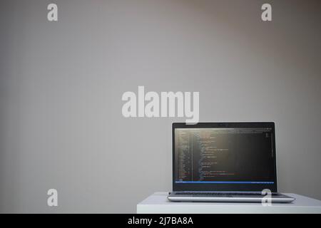 Opened laptop with code on the screen on the table Stock Photo