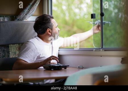 motorhome travel concept. Man controling a drone.a man controls a drone from the window of a motorhome Stock Photo