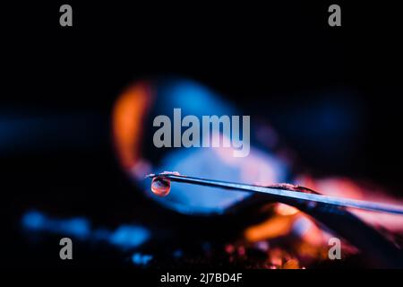 Tip of a syringe needle with a drop of heroin cooked in it. Concept of drug addiction. Copyspace. Stock Photo