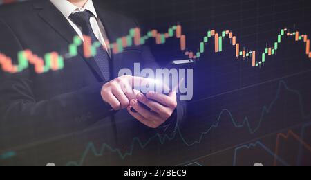 Man using smartphone with graphs analysis candle line and foreign currency rate on bokeh colors light. Manager analyzing investment statistics and ind Stock Photo