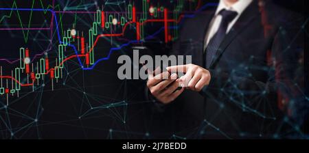 Man using smartphone with graphs analysis candle line and foreign currency rate on bokeh colors light. Manager analyzing investment statistics and ind Stock Photo