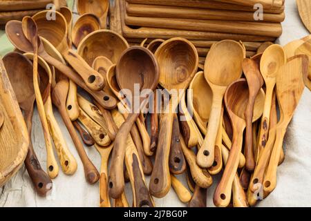 Wooden spoons lie on the surface with ornament. Various wooden utensils in vintage style. Household utensils are sold at the fair. Rural market Latvia Stock Photo