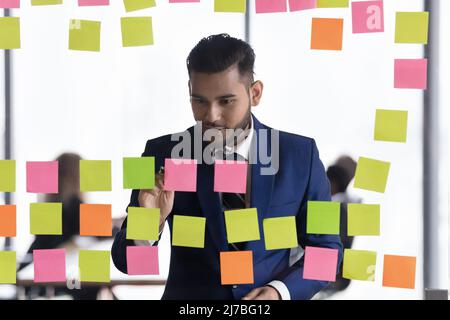 Positive engaged millennial business leader man writing notes Stock Photo