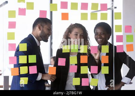 Happy multiethnic business team writing tasks on colorful notes Stock Photo