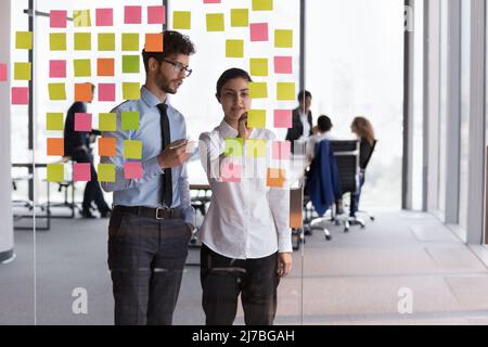 Confident Indian mentor woman teaching young Intern guy Stock Photo