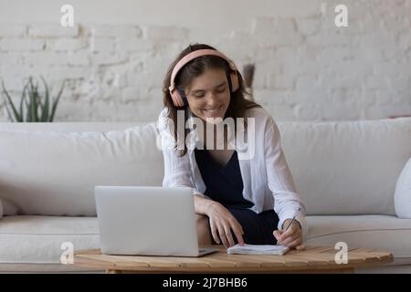 Positive engaged young student girl in trendy wireless headphones Stock Photo